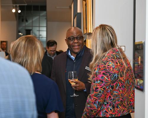 Male alumni holding wine glass smiling talking to woman at Birmingham 校友 event.