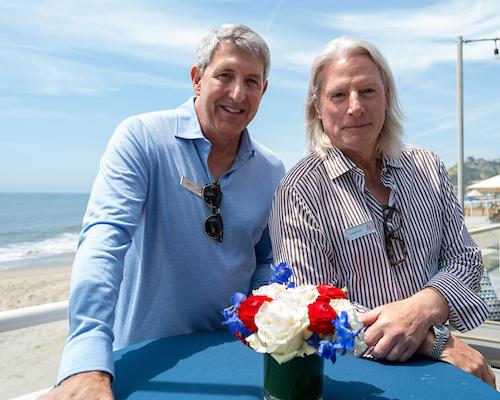 Two alumni in front of beach at Los Angeles 校友 event.